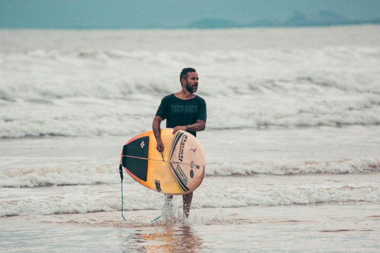 homem saindo do mar com sua prancha de surf